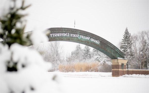  的 entrance arch to Grand Valley State University is seen among snow-covered trees. 