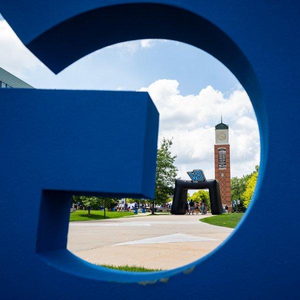 Clock tower seen through a giant blue G.