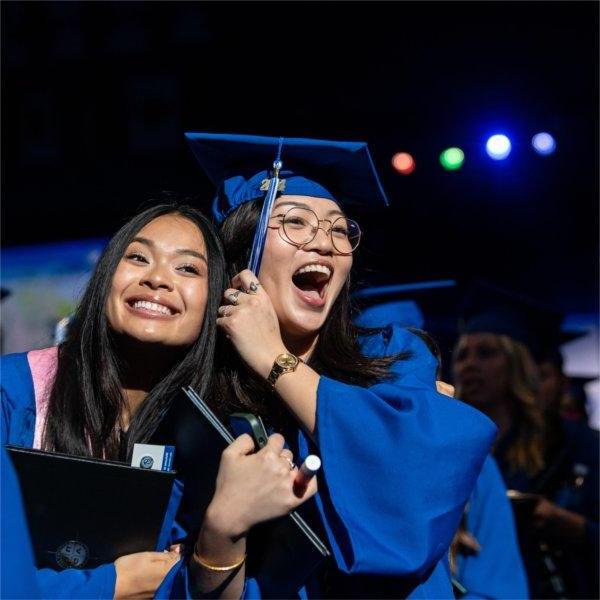 Two graduates react with joy after receiving their diplomas.